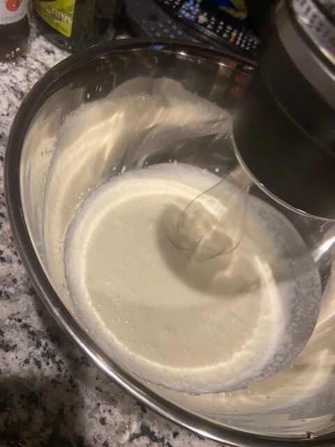 Whipping cream in a bowl with an electric beater