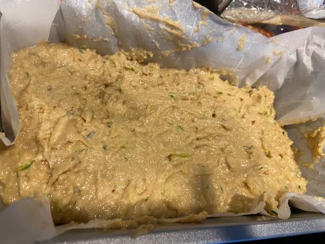 Raw zucchini bread batter in bread pan lined with parchment paper