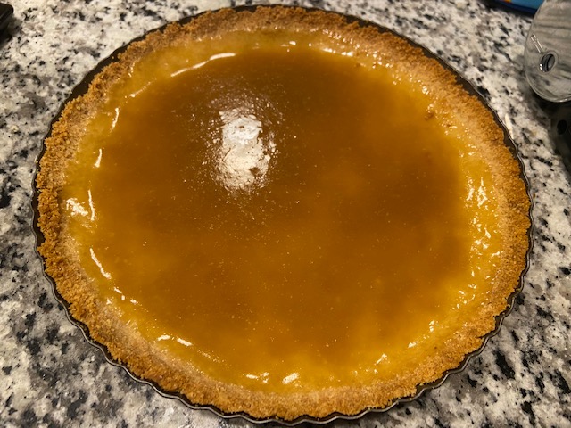 Butterscotch tart with the butterscotch freshly poured into the tart. A shiny, golden colored liquid